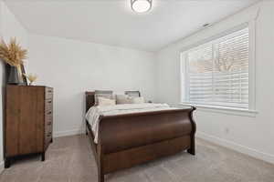 Carpeted bedroom with a textured ceiling and baseboards