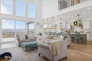 Living room with light wood-style floors, a chandelier, a towering ceiling, and a mountain view