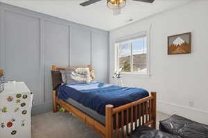 Bedroom with carpet floors, a decorative wall, and a ceiling fan