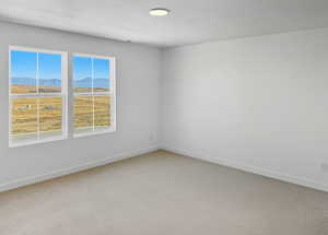 Empty room with a mountain view, a textured ceiling, and light carpet