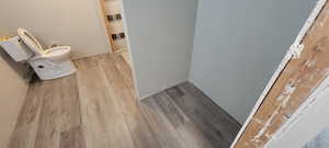 Unfinished Bathroom with wood finished floors and toilet