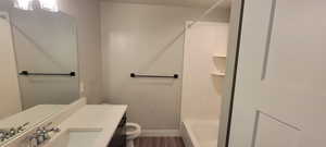 Hall bathroom with vanity, bathing tub / shower combination, and dark wood-style flooring