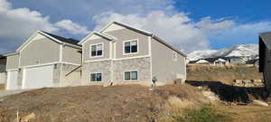 View of home's exterior with stone siding, a garage, and board and batten siding