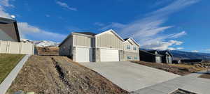 View of home's exterior with board and batten siding, a mountain view, a garage, concrete driveway, and stone siding