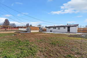 Back of house with a fenced backyard, a shed, and a patio area