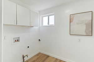 Laundry area with washer hookup, light wood-style floors, hookup for a gas dryer, hookup for an electric dryer, and cabinet space