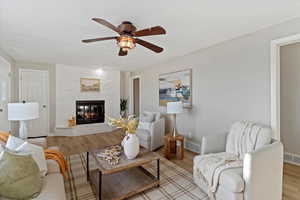 Living room featuring ceiling fan, a tile fireplace, and wood finished floors