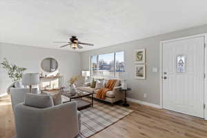 Living area with light wood-style floors, a textured ceiling, and a ceiling fan