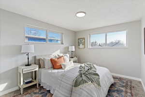 Bedroom with dark colored carpet, a textured ceiling, and multiple windows
