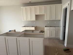 Kitchen with wood finished floors, a center island, and white cabinets
