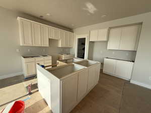 Kitchen with a center island, wood finished floors, a textured ceiling, and white cabinetry