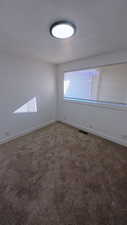 Empty room with dark carpet and baseboards