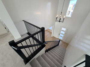 Stairway featuring a towering ceiling and a chandelier