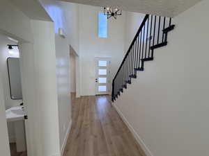 Entryway with stairway, light wood-style floors, and a high ceiling
