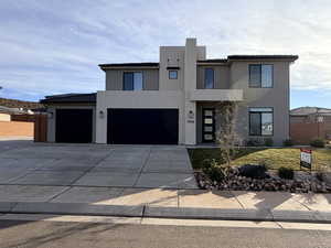Modern home featuring stucco siding, driveway, a tiled roof, and a garage