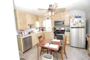 Kitchen featuring light brown cabinets, appliances with stainless steel finishes, light countertops, a textured ceiling, and light wood finished floors