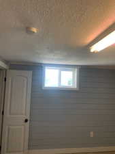Window with white trim set into light blue shiplap walls, featuring a white paneled door with black hardware