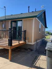 Exterior featuring beige vertical siding, a dark green gable accent, and a green shingle roof