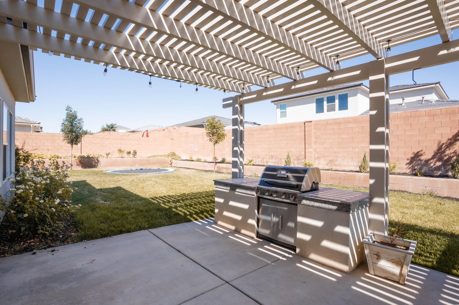Fenced backyard with a pergola, a patio, and exterior kitchen