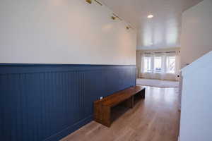 Hall featuring a wainscoted wall, wood finished floors, and recessed lighting