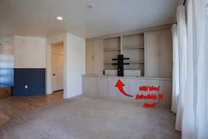 Unfurnished room featuring wainscoting, built in shelves, recessed lighting, carpet floors, and wood finished floors
