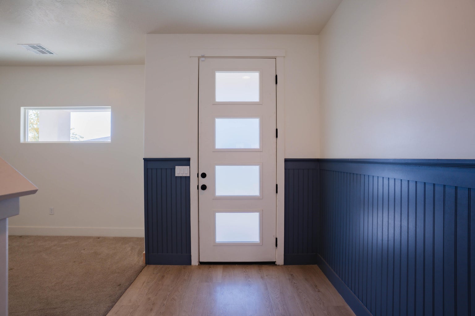 Entryway with light wood-type flooring and a wainscoted wall