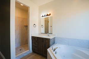 Full bathroom featuring vanity, a shower stall, a jetted tub, and light wood finished floors