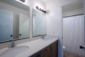 Full bath with double vanity and a shower with curtain
