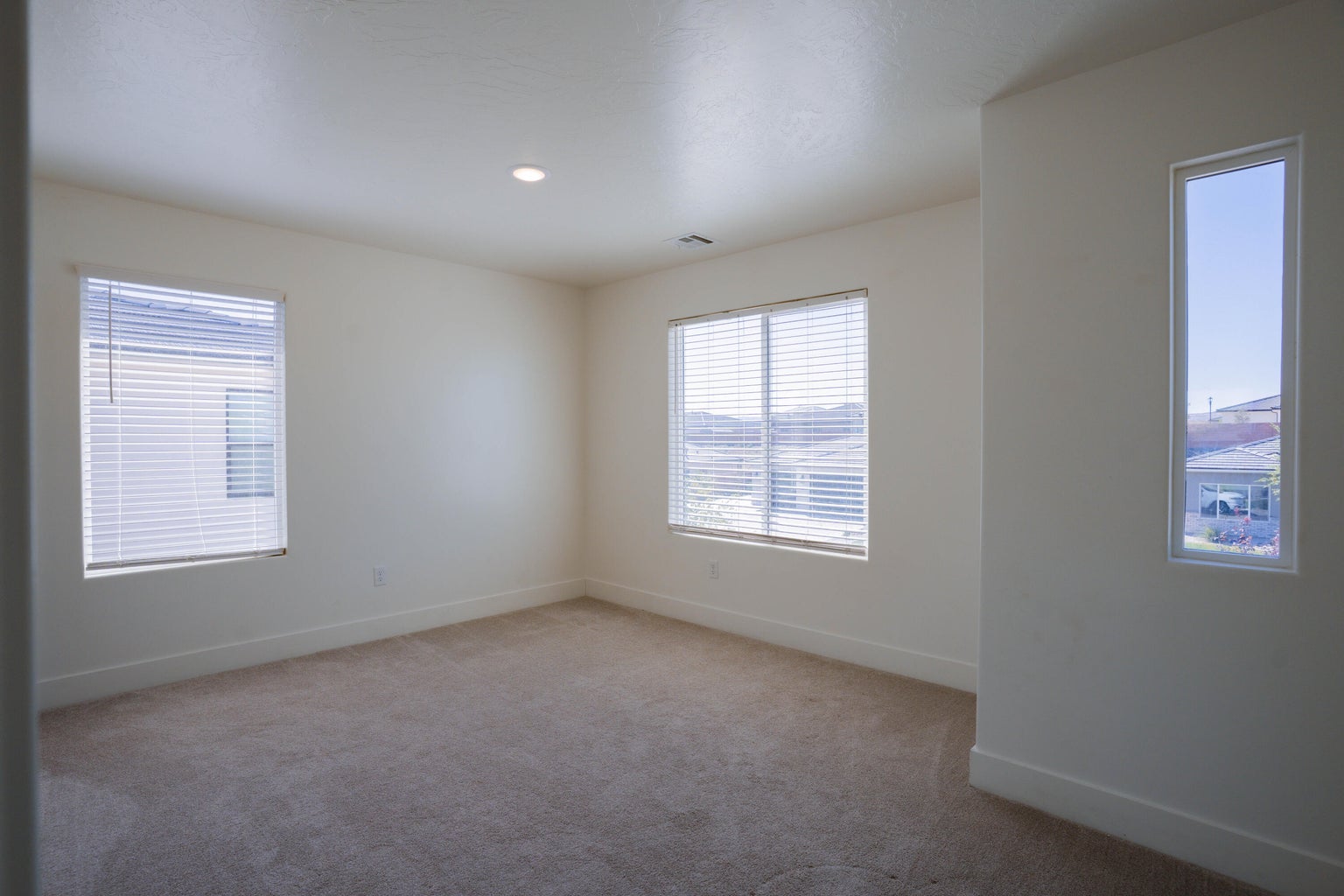 Spare room featuring light colored carpet, plenty of natural light, and recessed lighting