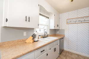 Kitchen featuring stainless steel dishwasher and white cabinets