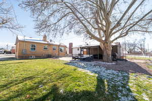 Back of property with a chimney, a patio, brick siding, and a yard