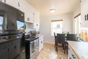 Kitchen with stainless steel appliances, white cabinetry, and light countertops