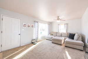 Carpeted living room with baseboards and a ceiling fan