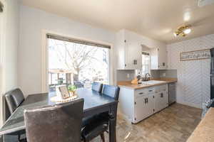 Kitchen with light countertops, white cabinets, stainless steel dishwasher, and stone finish flooring