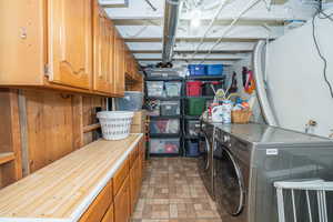 Laundry room with cabinet space, brick patterned flooring, and washer and dryer