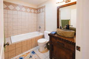 Full bathroom featuring vanity, tiled shower / bath combo, and tile patterned flooring