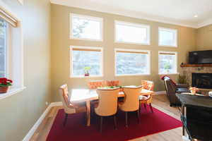 Dining space with light wood-style flooring, a fireplace, and crown molding