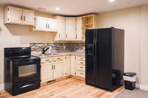 Kitchen with black appliances, open shelves, light countertops, tasteful backsplash, and recessed lighting