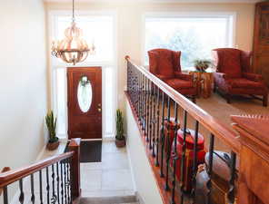 Foyer with a chandelier, tile patterned flooring, and stairs