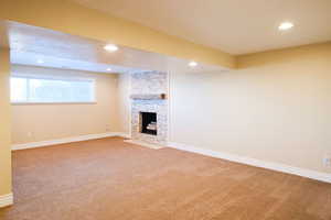 Unfurnished living room with light colored carpet, a fireplace, and recessed lighting