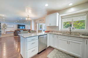 Kitchen with white cabinets, light stone countertops, dishwasher, recessed lighting, and open floor plan