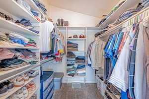 Walk in closet with vaulted ceiling and light carpet