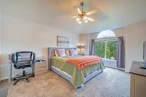 Bedroom with ceiling fan, light colored carpet, and a desk