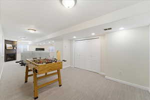 Game room featuring light colored carpet, recessed lighting, and a glass covered fireplace