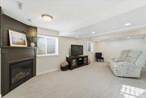 Living room featuring a glass covered fireplace and light carpet