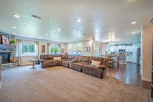 Living room with a textured ceiling, a fireplace, recessed lighting, dark carpet, and a chandelier