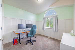 Office featuring a decorative wall, a wainscoted wall, lofted ceiling, and carpet flooring