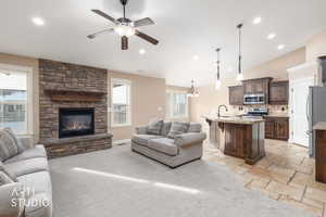 Living area featuring pendant lighting, vaulted ceiling, a ceiling fan, recessed lighting, and a stone fireplace.