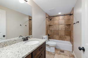 Full bath featuring stone tile floors, vanity, tub / shower combination, and recessed lighting.