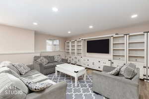 Living area with wood finished floors,  recessed lighting, and freestanding wall unit.